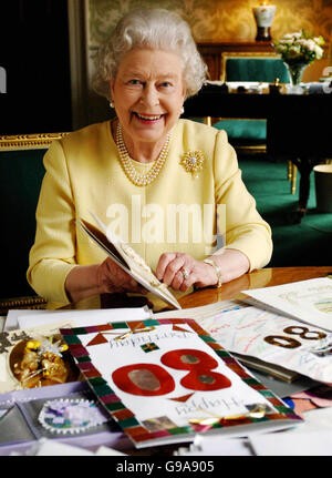 Königin Elizabeth II. Sitzt im Regency Room des Buckingham Palace in London, während sie sich einige der Karten ansieht, die ihr zu ihrem 80. Geburtstag zugeschickt wurden. Stockfoto