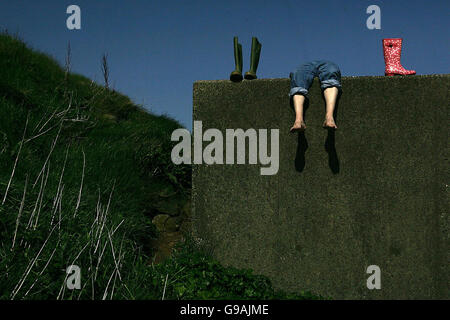 Ein nicht identifizierter Landwirt macht eine Pause von seiner Arbeit, um die Sonne entlang der Küstenstraße in den Glens of Antrim, Nordirland, zu genießen. Stockfoto