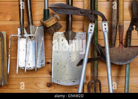 Gartengeräte in einem hölzernen Schuppen hängen. Stockfoto