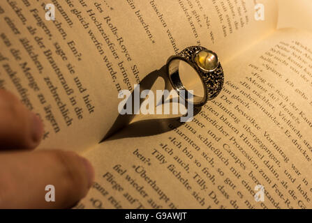 Ring wirft einen herzförmigen Schatten in Buch. Stockfoto