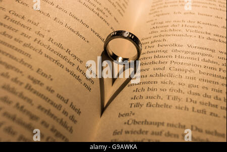 Ring wirft einen herzförmigen Schatten in Buch. Stockfoto