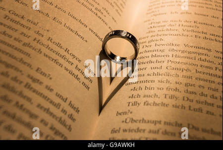 Ring wirft einen herzförmigen Schatten in Buch. Stockfoto