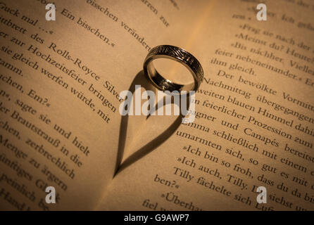 Ring wirft einen herzförmigen Schatten in Buch. Stockfoto