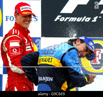 Ferrari-Pilot Michael Schumacher sprüht Champagner auf den spanischen und Renault-Fahrer Fernando Alonso, während sie nach dem Grand Prix von Großbritannien in Silverstone auf dem Podium feiern. Stockfoto