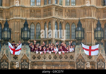 Kinder der Christchurch School in London helfen, zwei England-Flaggen von einem Balkon im House of Lords in Zentral-London aufzuhängen. Stockfoto