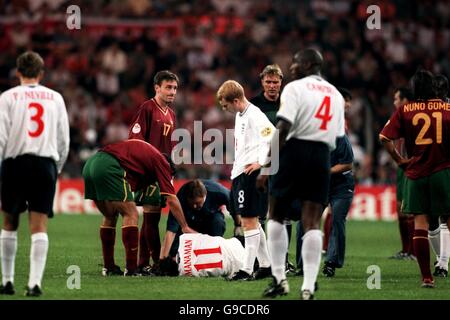 Besorgte Spieler versammeln sich um Englands Steve McManaman, als er lügt Verletzt Stockfoto