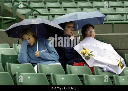 Tennis - Wimbledon. Am ersten Tag der wimbledon Championships schützen sich Fans vor Regen auf Platz 1. Stockfoto