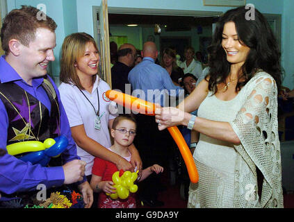 Die in Wales geborene Hollywood-Schauspielerin Catherine Zeta Jones trifft Matt, den Magischen Mann, und macht Ballontiere, während ihres Besuchs im Children's Hospital am University Hospital of Wales in Cardiff, Wales. Stockfoto