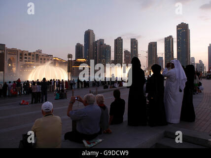 Zuschauern die Wasser-Anzeige der Dubai Fountain am Burj Khalifa Lake in der Abenddämmerung, Downtown Dubai, Vereinigte Arabische Emirate Stockfoto