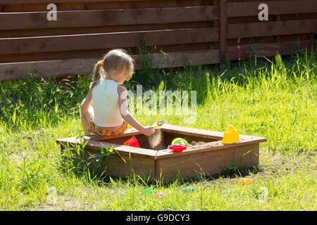 kleines Mädchen sitzend spielen in einer Sandbox Stockfoto