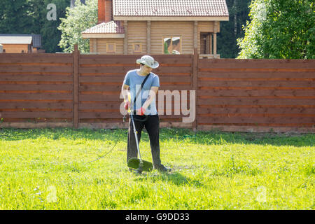 Mann mäht den Rasen mit einem Rasentrimmer Stockfoto