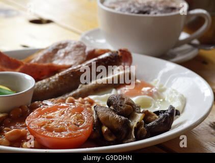 Komplettes warmes Frühstück mit Speck, Wurst, Pilzen und Tomaten Stockfoto