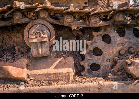 Rusty und Schmutz bedeckt mechanische Caterpillar Track mit Alter Räder und Rollen. Stockfoto
