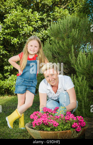 Familie alle Gartenarbeit. Tochter mit ihrer Mutter im Garten bepflanzen Blumen. Stockfoto