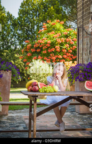 Fruchtige Lächeln Mädchen essen eine Vitamin in Form von Nektarinen. Stockfoto