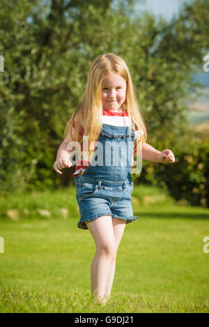 Sommer spielen kleine schöne blonde Mädchen auf dem grünen Rasen Stockfoto