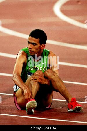 Olympische Spiele 2000 in Sydney - Leichtathletik - 1500 m der Männer - Finale. Der Marokkaner Hicham El Guerrouj sitzt auf der Strecke niedergeschlagen, nachdem er in die Silber-Position geschlagen wurde Stockfoto