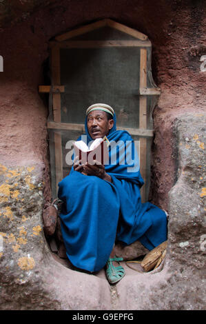 Priester liest Bibel vor einem Mönch Grab in Lalibela, Äthiopien Stockfoto