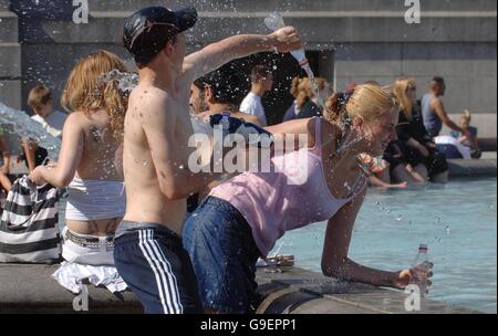 Junge Leute spielen in einem Trafalgar Square Brunnen im Zentrum von London, um sich abzukühlen, während die Temperaturen im ganzen Land ansteigen. Stockfoto