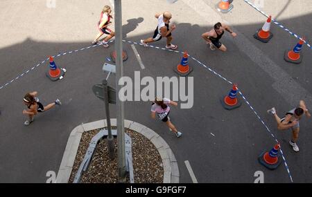 Männer und Frauen laufen auf den Straßen der Docklands während des Michelob ULTRA London Triathlon in London. Stockfoto