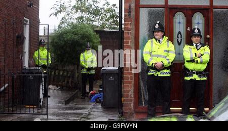 Die Polizei von Greater Manchester steht vor zwei der drei Häuser in der Gegend von Cheetham Hill, wo zwei Männer bei Anti-Terror-Razzien verhaftet wurden. Stockfoto