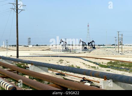 Pumpjacks, auch bekannt als Ölpferd, nickender Esel, Öljäger, Balkenpumpe, die Rohöl in der Bahrain-Wüste bei Sakhir am Persischen Golf fördert Stockfoto