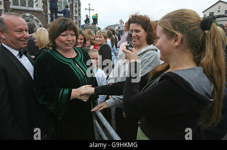 Die irische Gesundheitsministerin Mary Harney und ihr Mann treffen auf Einheimische, als sie zur Hochzeit von River Dance-Star Michael Flatley und der Tänzerin Niamh O'Brien in der St. Patrick's Church in Fermoy, Co Cork, ankommen. Stockfoto