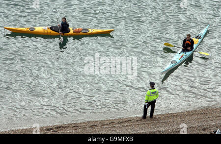 Die Säuberungsaktion an der Küste in der Nähe von Branscombe, Devon, wird fortgesetzt. Ein Polizist plaudert mit einem Paar Kajakfahrer. Stockfoto