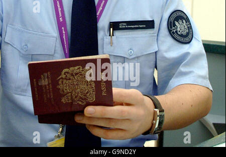 Ein Einwanderungsbeamter mit neuer Uniform überprüft einen Reisepass eines Passagiers, der am Terminal 1 des Flughafens Heathrow ankommt. Stockfoto