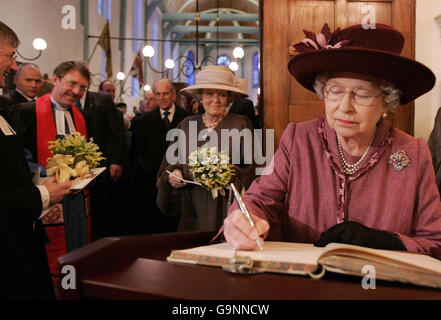 Die britische Königin Elizabeth II. (Rechts) signiert das Gästebuch in der englischen reformierten Kirche am Begijnhof in Amsterdam, Niederlande. Stockfoto