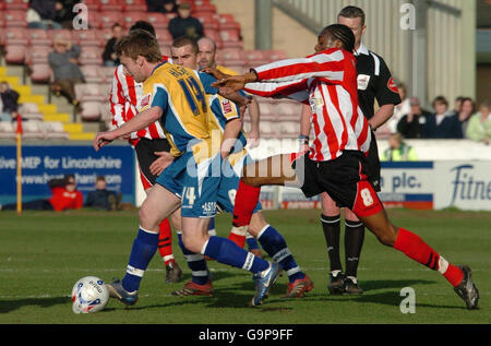 Lincoln's Dany N'Guessan (rechts) räumt einen Freistoß mit einem Rückstoß auf Mansfields Brian Hodge während des Coca-Cola Football League Two Spiels in Sincil Bank, Lincoln. Stockfoto