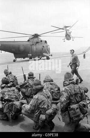 Marines hocken auf dem Flugdeck von HMS Hermes als Sea King Hubschrauber starten für eine Übung. Stockfoto