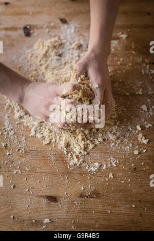 Zwei starke Hände eines Bäckers, die manuell auf eine raue, Holz Küchentisch Teig kneten sind in Nahaufnahme Stockfoto