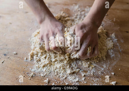 Zwei starke Hände eines Bäckers, die manuell auf eine raue, Holz Küchentisch Teig kneten sind in Nahaufnahme Stockfoto