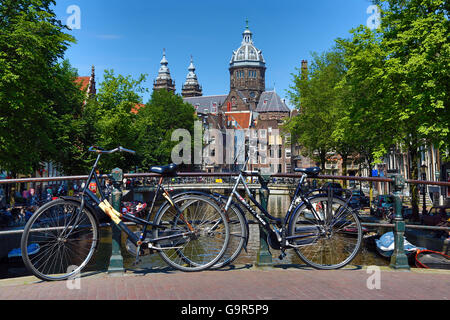 Fahrräder auf eine Kanalbrücke und die Basilika des Heiligen Nikolaus in Amsterdam, Holland Stockfoto