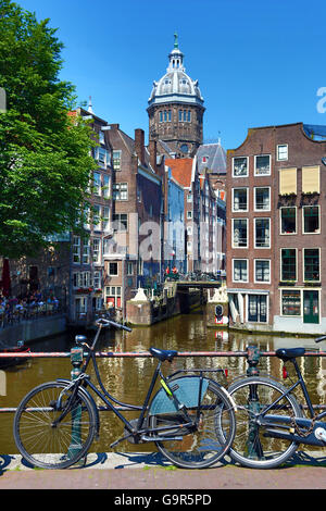 Fahrräder auf eine Kanalbrücke und die Basilika des Heiligen Nikolaus in Amsterdam, Holland Stockfoto