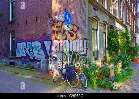 Fahrräder parken auf der Straße mit Graffiti in Amsterdam, Holland Stockfoto