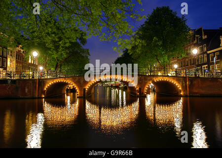 Beleuchtete Kanalbrücke in der Nacht auf den Kanal zwischen Prinsengracht und Brouwersgracht in Amsterdam, Holland Stockfoto