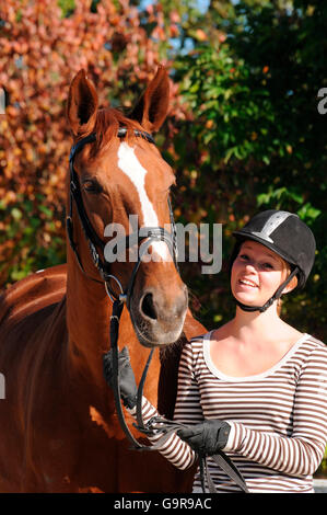 Mädchen mit deutschen Warmblut / Sorrell, Trense, Reiten Helm Stockfoto