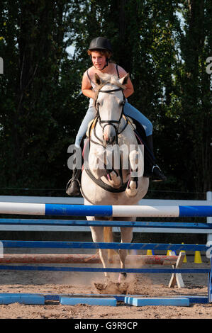 Mädchen auf Deutsch Reiten Pony / Springturnier, Reithelm, Reitplatz, Hürde Stockfoto