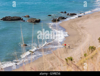 Fuengirola, Costa Del Sol, Provinz Malaga, Andalusien, Südspanien.  Zwei Menschen spazieren am Strand Carvajal im Winter. Stockfoto