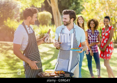 Männer mit einer Bierflasche während der Vorbereitung der Barbecue-grill Stockfoto