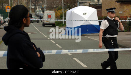 Ein Freund von Paul Erhahon (der nicht genannt werden wollte) schaut sich die Szene auf der Hall Road, Leytonstone, Ost-London, an, nachdem der 14-jährige Junge bei einem Bandmesser-Angriff tödlich erstochen wurde, der auch einen 15-Jährigen in einem kritischen Zustand zurückließ. Stockfoto