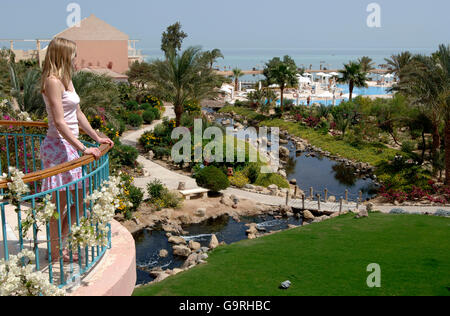 Junge Frau auf der Suche von Garten, Balkon, Hotel Mövenpick Resort, el-Guna, Ägypten / Mövenpick Resort Stockfoto