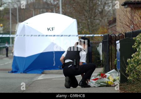 Ein Polizeibeamter legt in der Hall Road in Leytonstone, Ost-London, Blumen aus der Öffentlichkeit, nachdem gestern Abend ein 14-jähriger Junge gestorben war, nachdem er in kurzer Entfernung bei einem Bandenmesser-Angriff erstochen wurde, bei dem sich auch ein 15-Jähriger in einem kritischen Zustand befand. Stockfoto