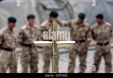 Britische Armeesoldaten stellen vor einem Hintergrund ein Kreuz dar, das Teil eines Denkmals ist, um an gefallene Kameraden in der Provinz Helman zu erinnern, als sie warten, um mit dem unsichtbaren britischen Finanzchef Gordon Brown im Camp Bastion im Süden Afghanistans zu sprechen. Stockfoto