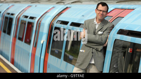 Künstler Jim Isermann mit der mit seinem Entwurf gemalten U-Bahn als Teil der laufenden Piccadilly-Linie Hundertjahrfeier, an der U-Bahnstation Northfields, West London. Stockfoto