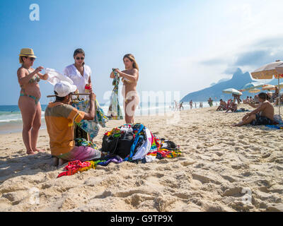 RIO DE JANEIRO, Brasilien - ca. März 2013: Kunden versuchen auf Ware von einem Händler in eine typische Szene am Strand von Ipanema. Stockfoto