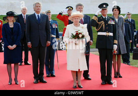 Die britische Königin Elizabeth II. Und der Herzog von Edinburgh (vorne) werden von dem französischen Premierminister Dominique de Villepin (3. Links), seiner Frau Marie-Laure (links), dem kanadischen Premierminister Stephen Harper (hinter Queen) und seiner Frau Laureen (vorne rechts - mit Baskenmütze) begleitet. Wie sie für die französische Nationalhymne während einer Zeremonie in der Vimy-Gedenkstätte, in der Nähe von Lille in Nordfrankreich, zur Aufmerksamkeit stehen. Stockfoto