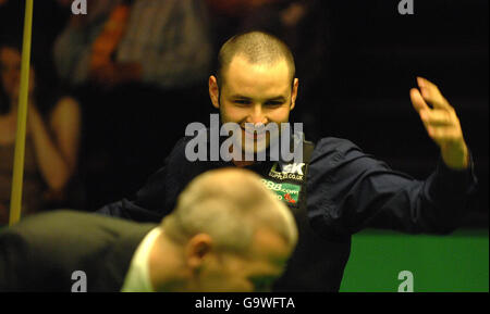 Der schottische Stephen Maguire lacht, als Schiedsrichter Jan Verhaas im Viertelfinalspiel bei den Snooker-Weltmeisterschaften im Crucible Theatre, Sheffield, vor ihm duckt. Stockfoto